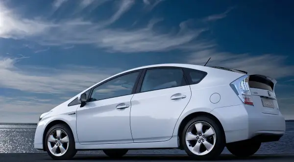 Biały Toyota Prius 3 na tle błękitnego nieba z chmurami.