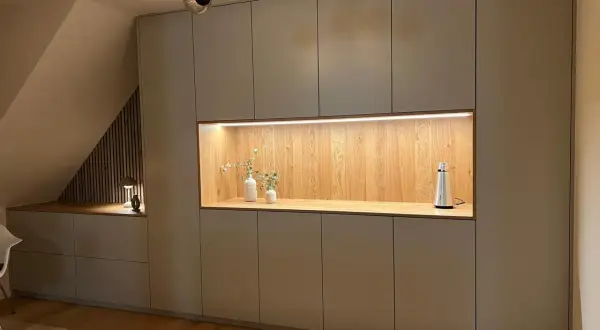 Moderne Einbauschränke gestalten eine gemütliche Schlafnische mit beleuchtetem Holzelement und Deko.