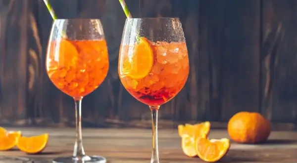 Dwa orzeźwiające Aperol Spritz z plasterkami pomarańczy i słomkami. Idealne na lato, a ich aperol spritz kcal nie są wysokie.