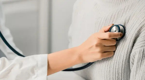 Un médecin écoute le cœur d'une patiente, cherchant un petit souffle au cœur.