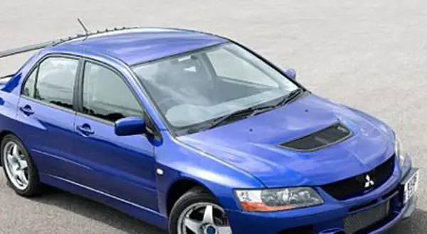 Niebieski Mitsubishi Lancer Evo 9 z charakterystycznym wlotem powietrza na masce i dużym spojlerem, gotowy do akcji.