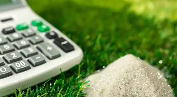 Calculadora sobre césped artificial, calculando la cantidad de arena para un proyecto de 100 m2.