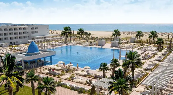 Luksusowy hotel Occidental Marco Polo nad morzem, z basenem, palmami i plażą.