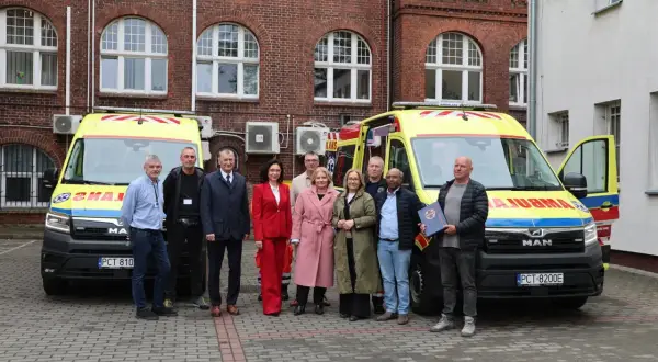 Grupa osób pozuje przed dwoma nowymi karetkami LPU. Rejestracja pojazdów zakończona, gotowi do służby.