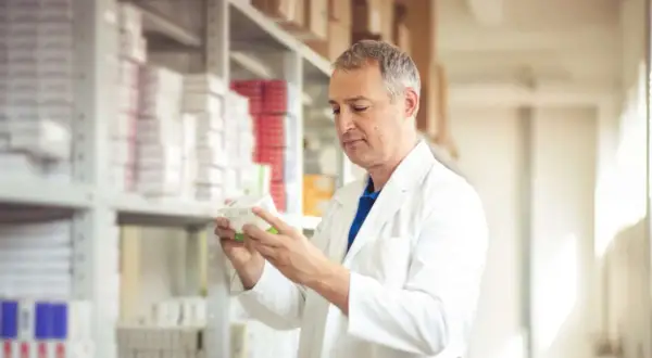 Farmaceuta w białym fartuchu analizuje lek. Zastanawiasz się, ile zarabia technik farmacji?