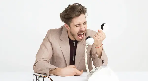 Mężczyzna krzyczy do telefonu, pokazując, co to egoizm. Obok leżą okulary.