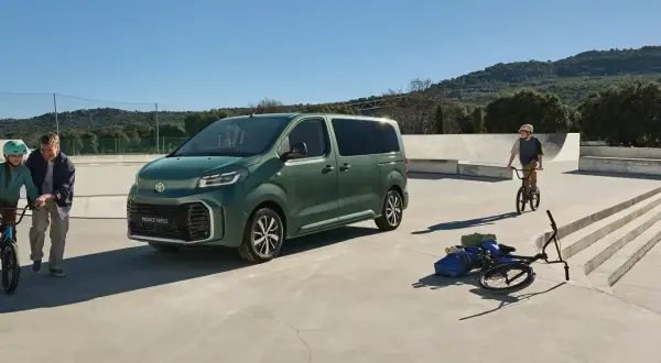 Grön Toyota Proace Verso parkerad vid en skatepark. En pappa och dotter med cyklar, en pojke på BMX.