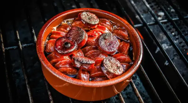 Heiß gegrillte Chorizo-Tapas in einer Tonschale, die auf einem Grillrost brutzeln.