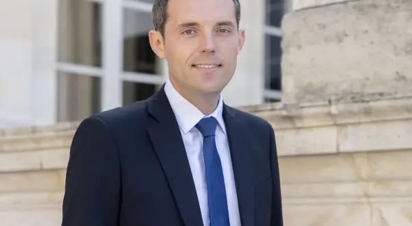 Alexandre Portier, souriant, en costume sombre, prêt pour son mariage.