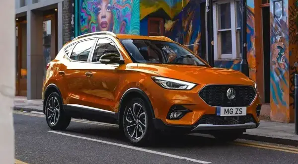 Pomarańczowe auto MG ZS na tle kolorowego muralu.