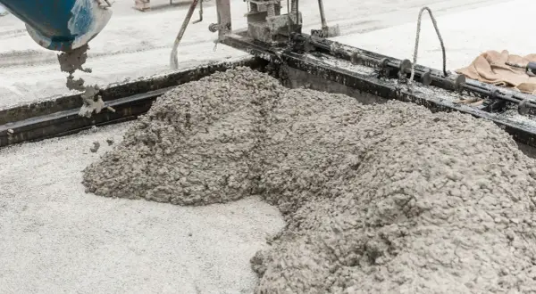 Beton wylewany z betoniarki na podsypkę z piasku pod kostkę.