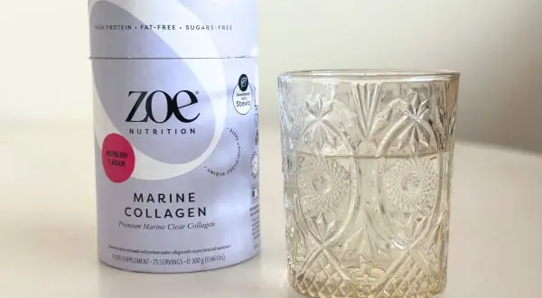 Opakowanie Zoe Nutrition Marine Collagen o smaku malinowym obok szklanki. Czy warto kupić? Sprawdź collagen drink dr max opinie.
