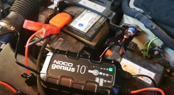 Ładowanie akumulatora na mrozie. Urządzenie NOCO Genius 10 podłączone do akumulatora samochodowego, by zapewnić mu energię w zimne dni.