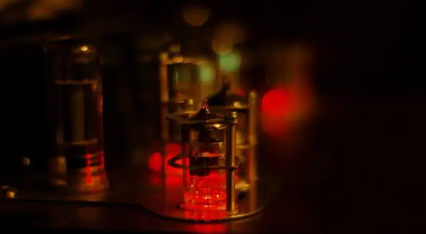 Czerwone żarzące się lampy elektronowe, jak w starym sprzęcie audio. W tle rozmyte światła, tworzące magiczny nastrój.