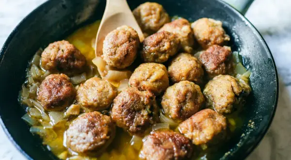 Polpette in bianco dorate e succulente, cotte in padella con cipolle dolci e un sughetto invitante. Un classico confortante.