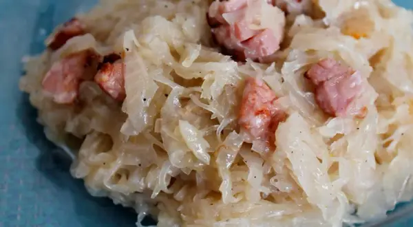 Kapusta kiszona zasmażana z boczkiem, podana na talerzu. Aromatyczne danie, które rozpływa się w ustach.