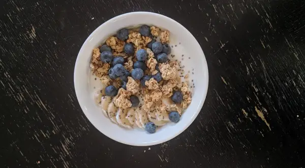 Un bol de skyr avec des myrtilles, des rondelles de banane et du granola. On peut chauffer le skyr pour un petit-déjeuner réconfortant.
