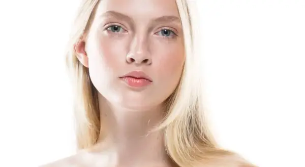 Młoda kobieta o jasnej cerze i blond włosach, uosobienie skandynawskiej urody. Delikatne rysy twarzy, błękitne oczy i subtelny rumieniec.