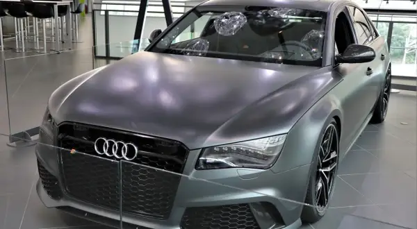 Matowy, szary Audi RS8 z czarnymi felgami i detalami, prezentowany w salonie.