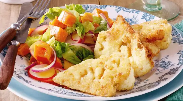Knuspriges Blumenkohl Schnitzel mit einem bunten Salat aus Kürbis, Radieschen und roten Zwiebeln auf einem blumengemusterten Teller.