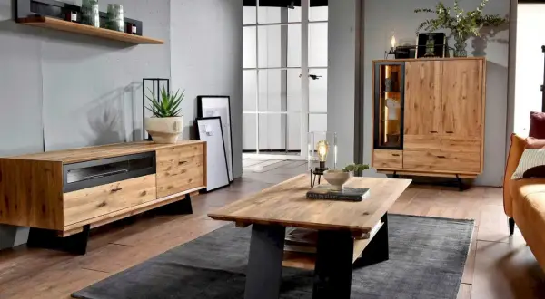 Przytulny salon w stylu boho loft. Drewniane meble, szara ściana i duża przeszklona drzwi tworzą ciepłą atmosferę.