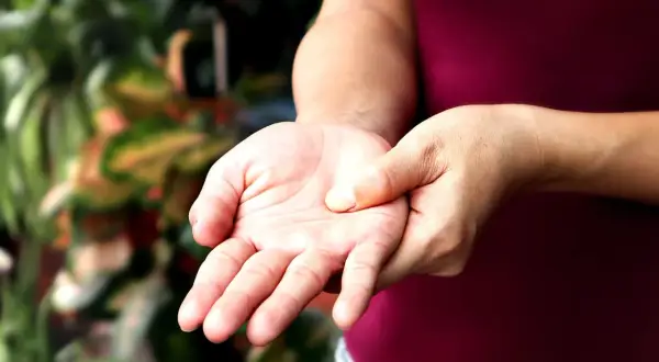 Mano che si tocca il polso, forse per un sintomo di polineuropatia.