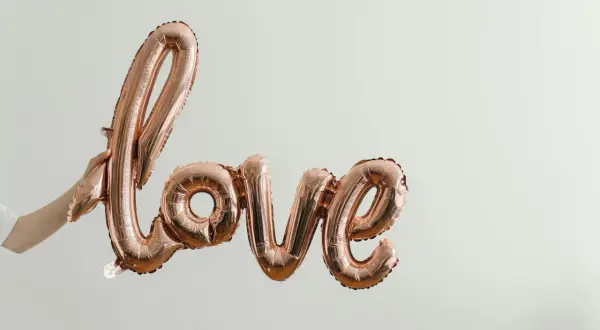 Różowe balony w kształcie napisu "Love" unoszą się w powietrzu. To symbol bezwarunkowej miłości matki do dziecka, jak w pięknych cytatach.