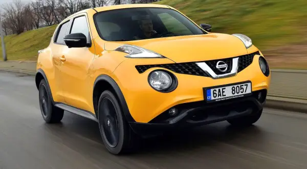 Żółty Nissan Juke pędzi po drodze, kierowca skupiony na trasie.