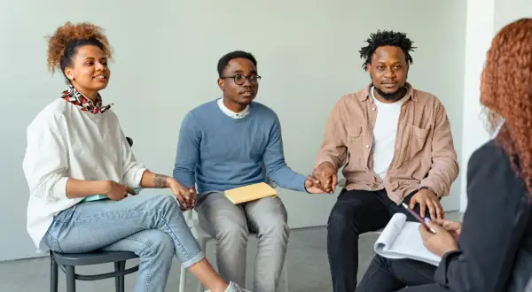 Grupo de personas en círculo, tomándose de las manos, fortaleciendo sus relaciones de amistad y apoyo mutuo.