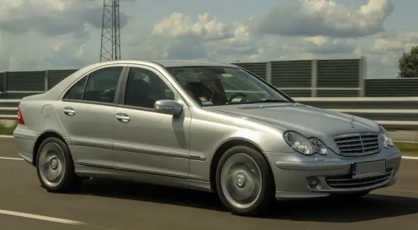 Srebrny Mercedes W203 2.2 CDI pędzi autostradą, chmury na niebie tworzą ciekawe kształty.