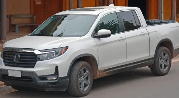 Biały Honda Ridgeline z błotem na progach, gotowy na przygodę.