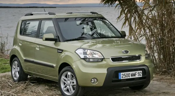 Zielony Kia Soul na tle jeziora i trzcin. Wiele osób szuka kia soul opinie przed zakupem.