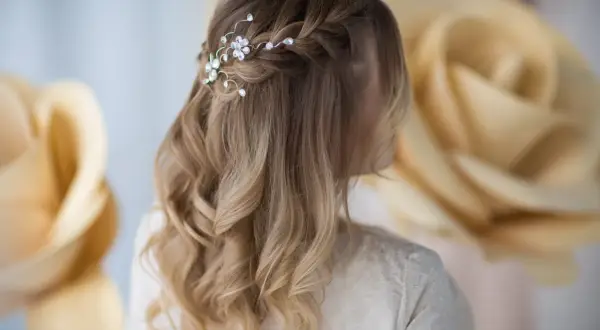 Eleganckie fryzury z warkoczem na wesele, ozdobione błyszczącymi kryształkami. Delikatne fale i subtelny warkocz tworzą romantyczny look.