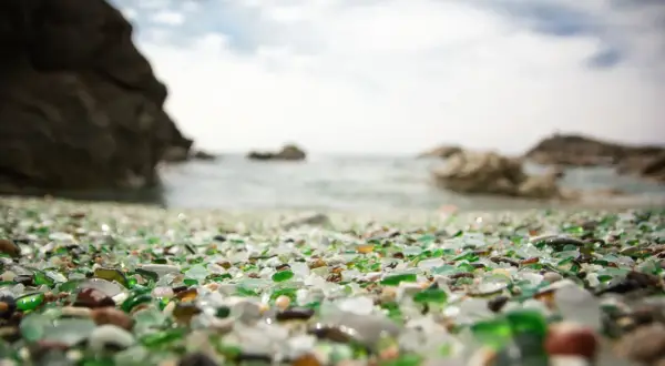 La playa de los cristales, un tesoro de vidrio pulido por el mar, se extiende ante rocas y el océano.