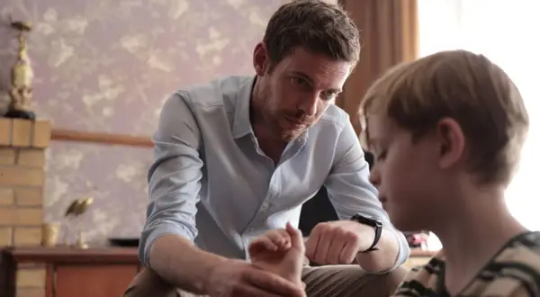 Ein Mann spricht mit einem Jungen, dessen Hand er hält. Die Szene erinnert an die Serie "Chemie des Todes".