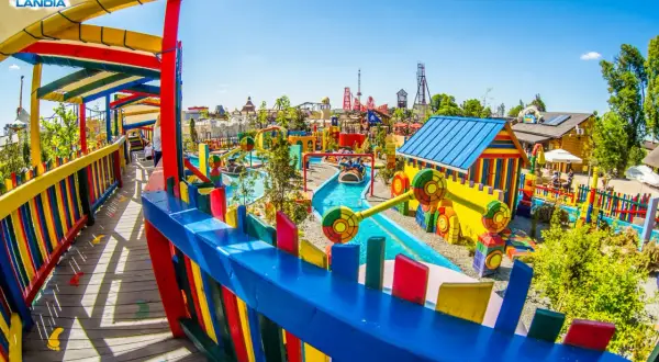 Kolorowy park rozrywki Energylandia, pełen atrakcji i bajkowych miejsc w Polsce. Dzieci pływają łódkami po wodnej trasie wśród kolorowych domków i zjeżdżalni.