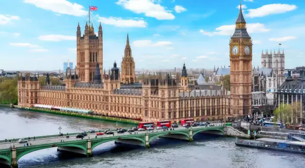 Parlamentshuset och Big Ben i London, med en bro och trafiken som visar det typiska klimat london.