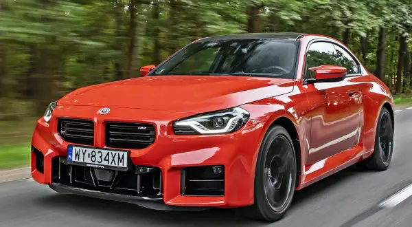 Pomarańczowe BMW M2 pędzi leśną drogą. Sprawdź aktualną bmw m2 cena i poczuj moc!