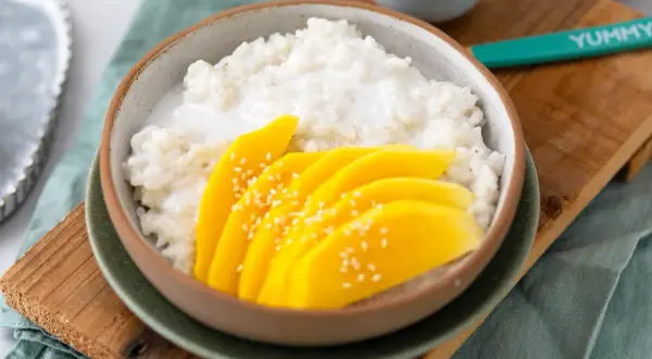 Ein Schälchen mit cremigem Klebreis und frischen Mangoscheiben, bestreut mit Sesam. Perfekt für ein Mango Sticky Rice Rezept.