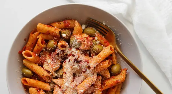 Penne z sosem pomidorowym, oliwkami i startą mozzarellą, posypane płatkami chili.
