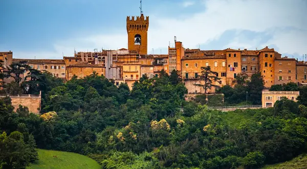 Un borgo storico su una collina verdeggiante, con una torre campanaria che domina la **città di Leopardi**.
