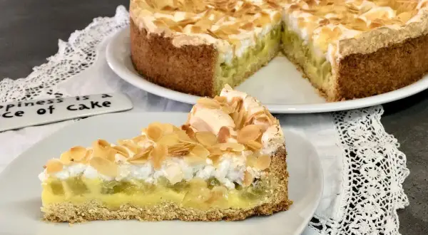 Ein köstlicher Rhabarberkuchen mit Pudding und Baiser, bestreut mit Mandelblättchen. Ein Stück Glück auf einem Teller.