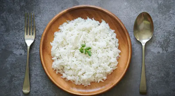 Piatto di riso bianco, forchetta e cucchiaio. Potrebbe essere l'inizio della dieta del riso 4 kg in 7 giorni.