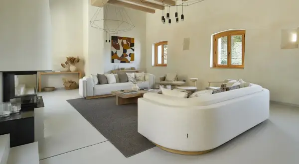 Salón moderno con sofás blancos, chimenea y suelo de microcemento sobre azulejos.