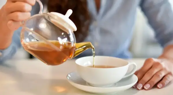 Kobieta nalewa aromatyczną herbatę z kopru włoskiego do filiżanki.