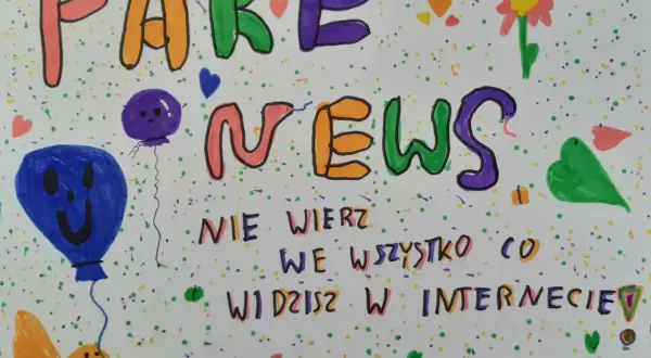 Kolorowe litery tworzą napis "FAKE NEWS". Poniżej, mniejszymi literami, widnieje ostrzeżenie: "NIE WIERZ WE WSZYSTKO CO WIDZISZ W INTERNECIE!". Obrazek ozdobiony jest balonami, kwiatkiem i serduszkami.