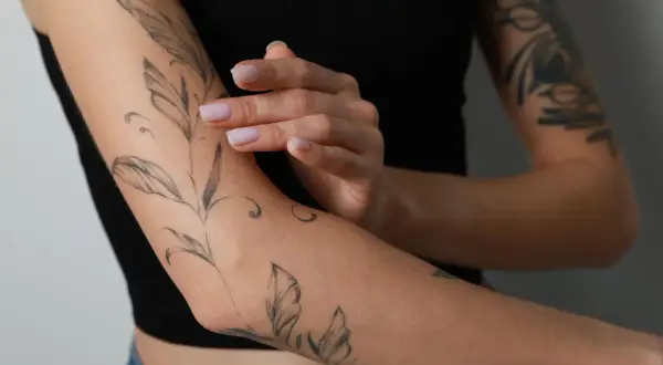Frauenarm mit Blatt-Tattoo. Das Tattoo schmerzt nach 4 Tagen, die Haut ist leicht gerötet.