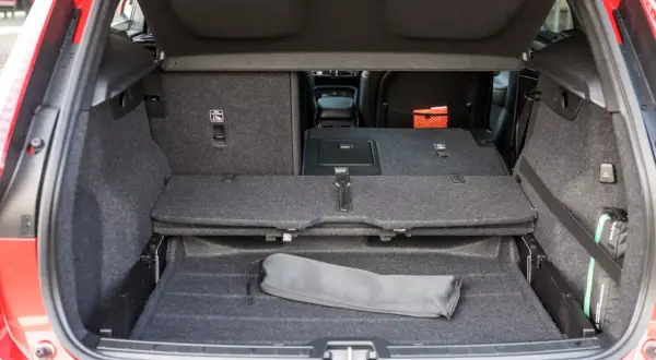 Bagagliaio aperto Volvo XC40, con sedili abbassati per massimizzare le volvo xc40 dimensioni. Si intravede un kit di pronto soccorso.
