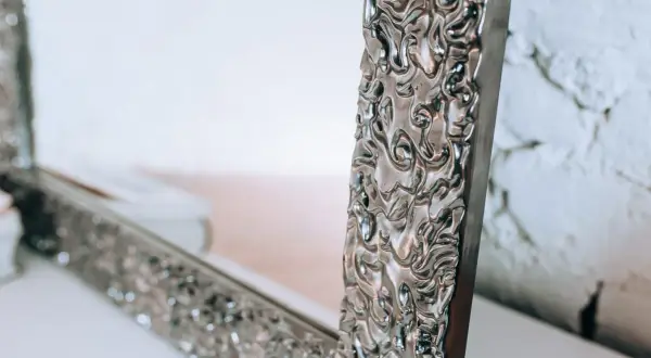 Eleganckie lustro do sypialni glamour z bogato zdobioną, srebrną ramą.