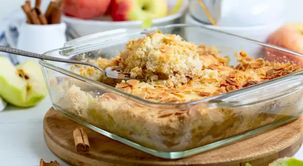 Ein goldbrauner Apfelkuchen mit knuspriger Streuseldecke und Mandelblättchen, bereit zum Servieren.